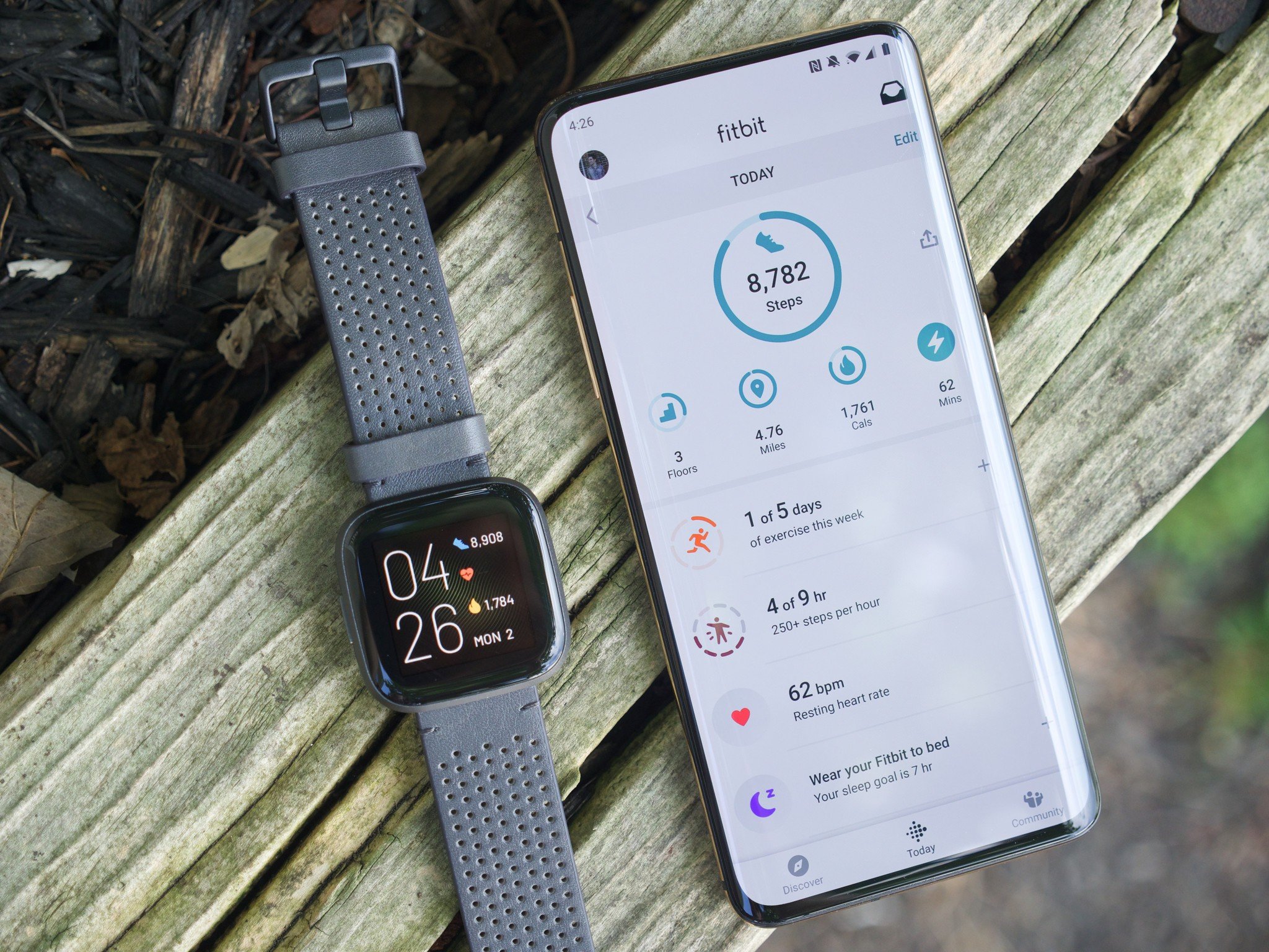Fitbit Versa 2 next to a OnePlus 7 Pro running the Fitbit mobile app
