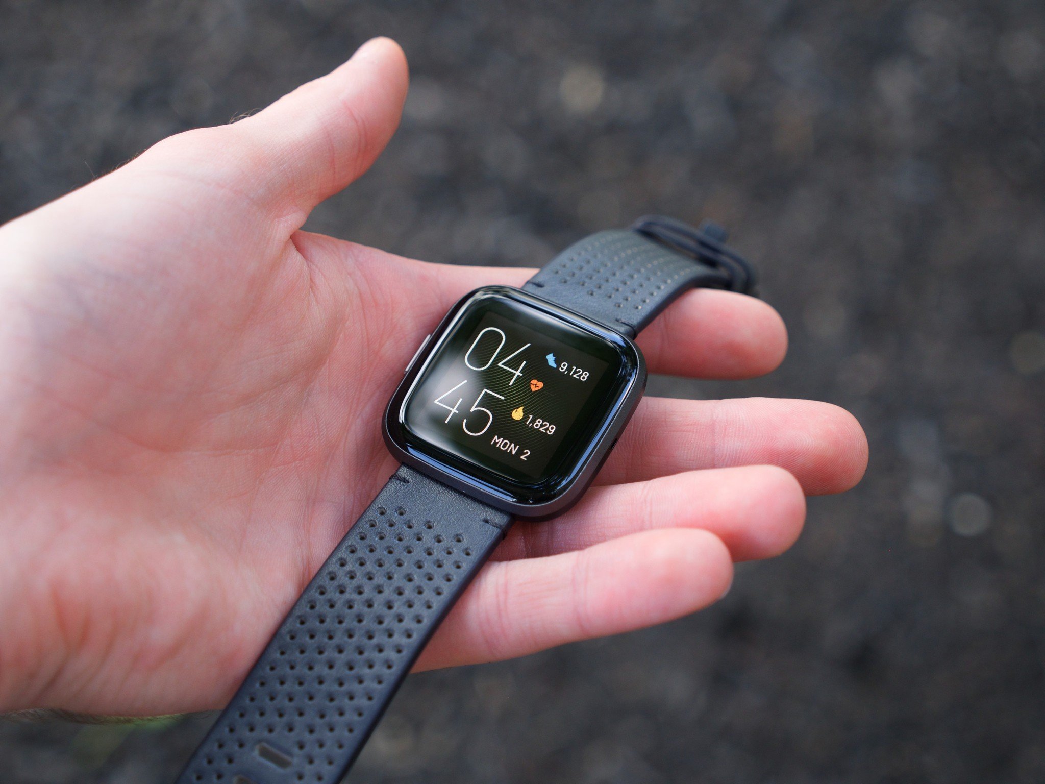 Fitbit Versa 2 with leather band being held