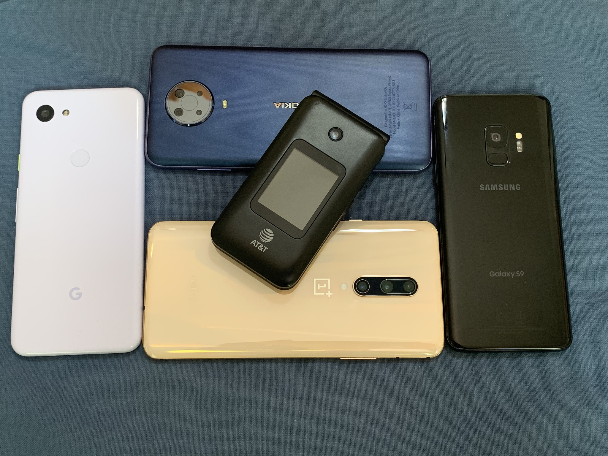 A flip-phone sitting on top of several smartphones
